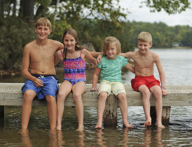 Maine Camp Life: Four children dangle their feet in the water off a pier at Crystal Lake near Harrison, Maine.