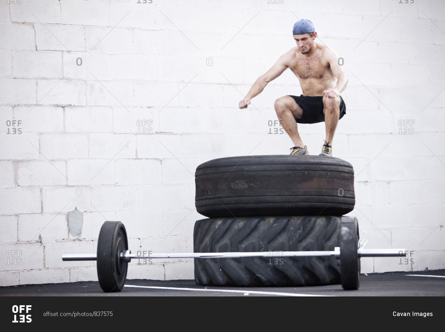 A young man jumps on tires while doing a fitness boot camp.