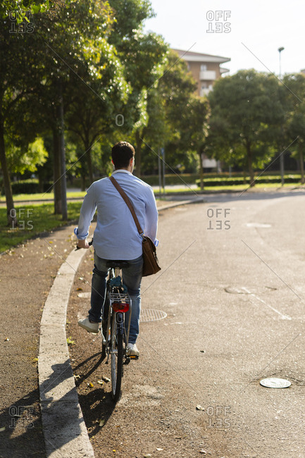 Rear view of young man riding a bicycle on road