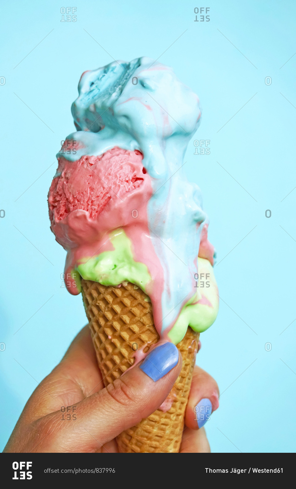 Womans Hand Holding Ice Cream Cone With Melting Ice Cream In Front Of Blue Background Stock 