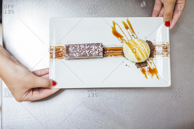 Junior chef with prepared dessert on plate- from above