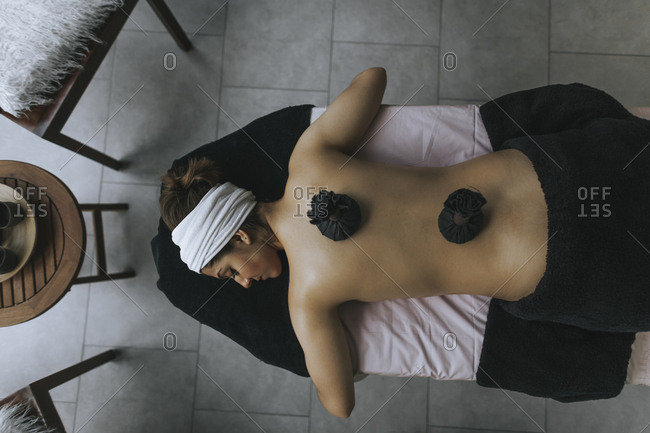Young woman with sachets on her back during stamp massage