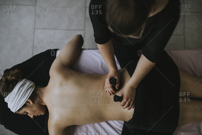 Young woman with sachets on her back during stamp massage