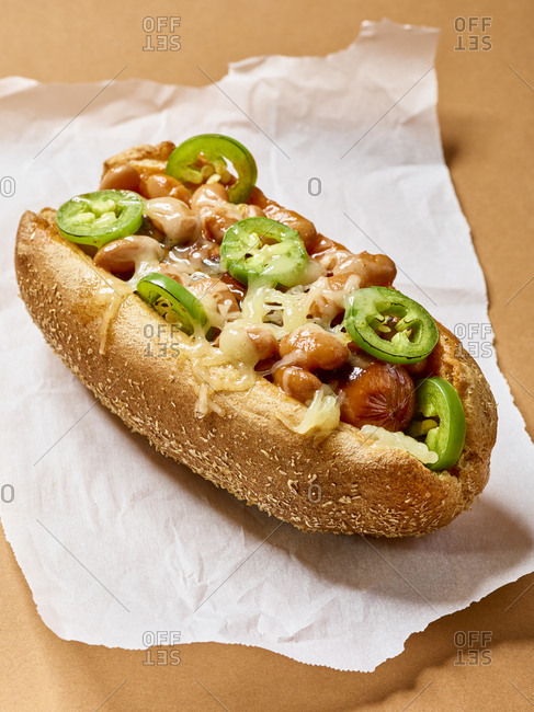 Hot dog topped with melted cheese, beans, and jalapenos