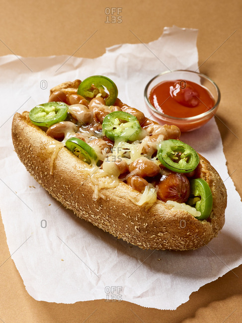 Hot dog topped with melted cheese, beans, and jalapenos