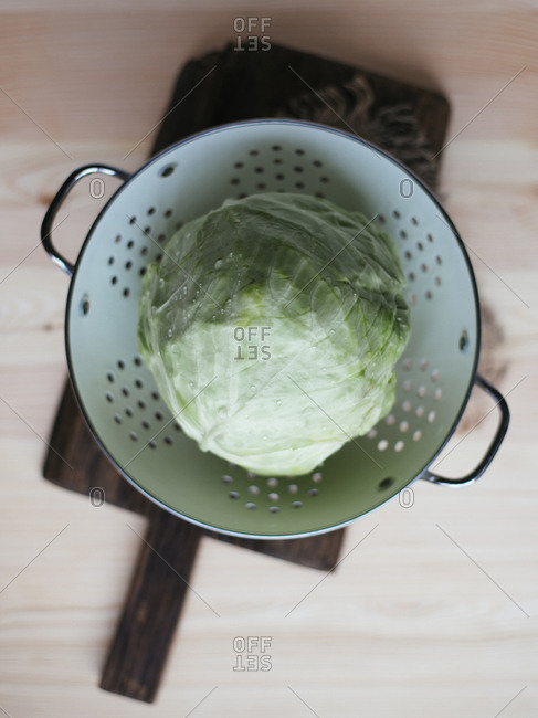 Raw fresh cabbage in colander on wooden table