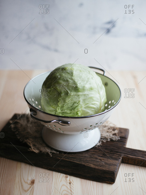 Raw fresh cabbage in colander on wooden table
