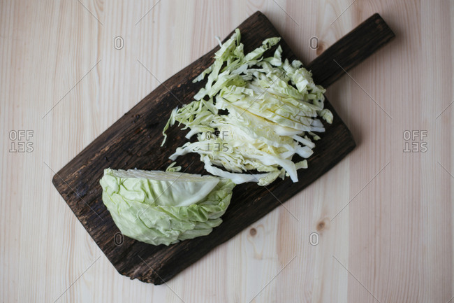 Raw fresh sliced cabbage on dark wooden cutting board