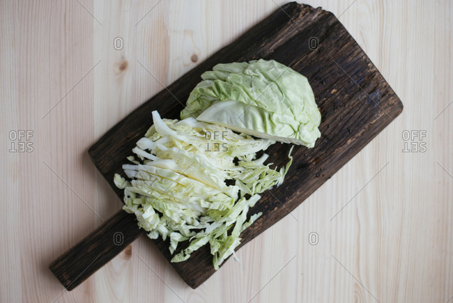Raw fresh sliced cabbage on dark wooden cutting board