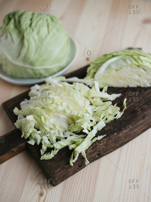Raw fresh sliced cabbage on dark wooden cutting board