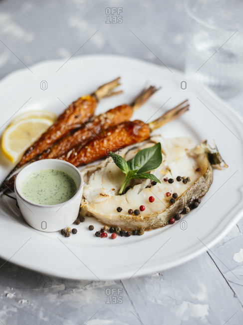 Fried codfish steak served with roasted carrot and sour cream basil salsa