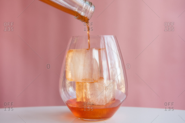 Liquor being poured into glass with ice cubes
