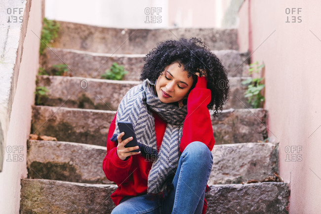 Young woman with smart phone sitting on steps
