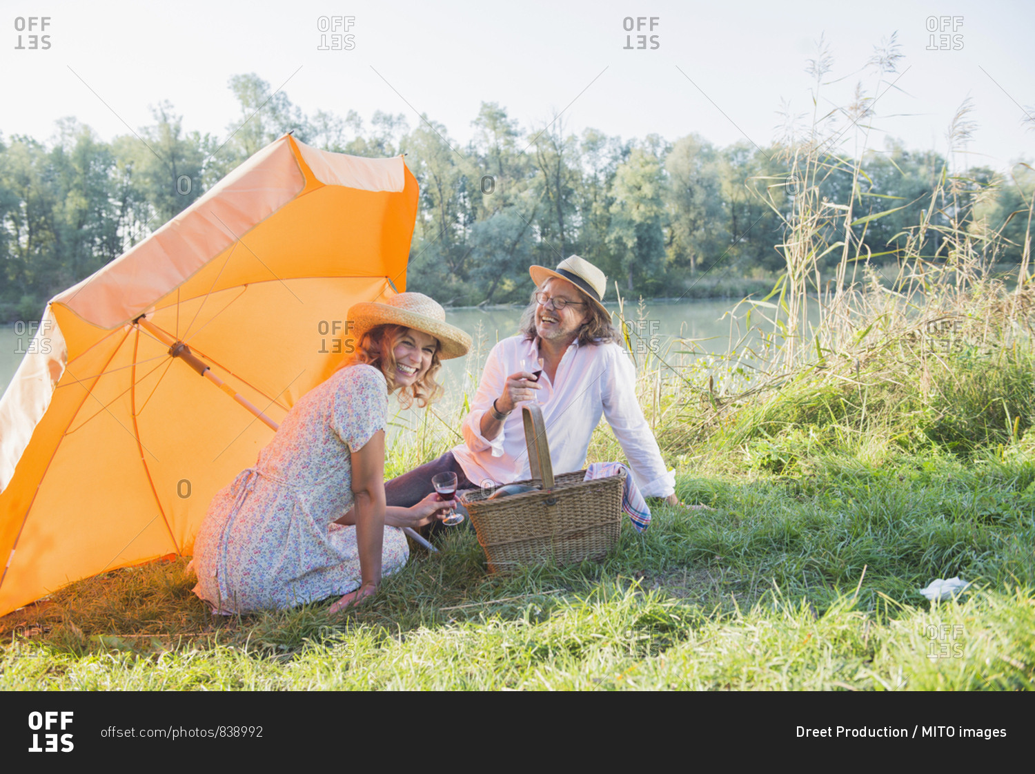 Couple having a picnic and drinking wine by lakeshore, Bavaria, Germany