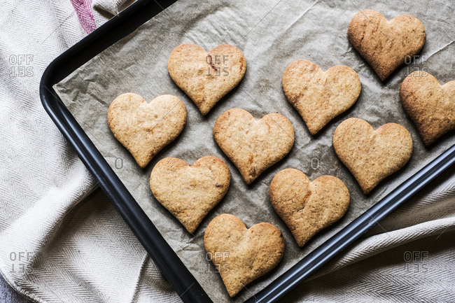 High angle close up of freshly baked hart-shaped cookies on baking tray.