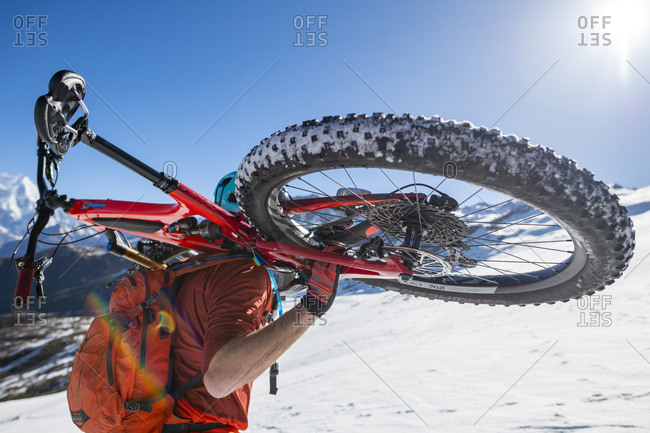 Gosainkund, Nepal - March 28, 2019: A mountain biker carrying his bike up a snow covered hillside in the Himalayas