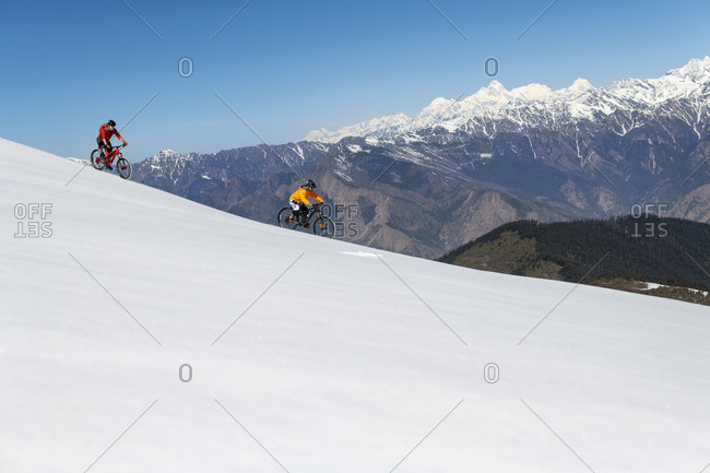 Gosainkund, Nepal - March 28, 2019: Mountain biking on a snow covered slope in the Himalayas with views of the Langtang mountain range