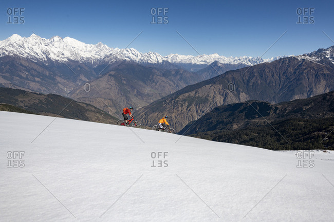 Gosainkund, Nepal - March 28, 2019: Mountain biking in the snow in the Himalayas with views of the Langtang mountain range in the distance