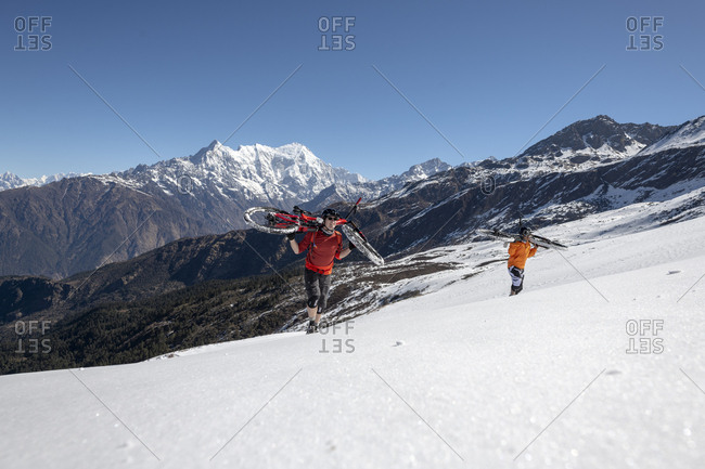 Gosainkund, Nepal - March 28, 2019: Mountain bikers carry their bikes up a snow covered slope in the Himalayas