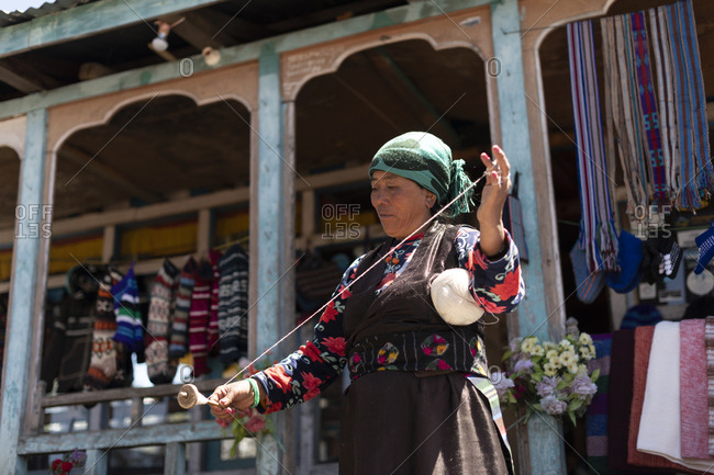 Gosainkund, Nepal - March 28, 2019: A Sherpa woman from Gosainkund spins baby Yak wool using the traditional method with a spindle