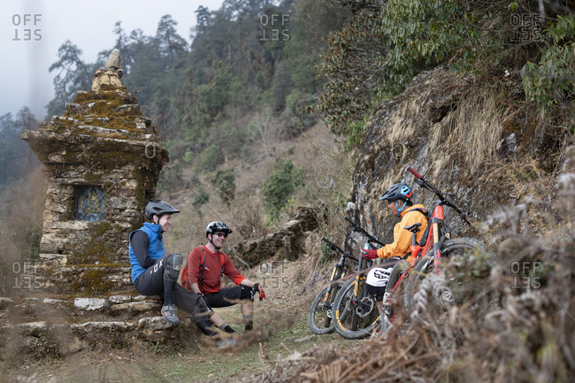 Gosainkund, Nepal - March 29, 2019: Mountain bikers take a break near a moss covered Tibetan chorten in the Himalayas in the Gosainkund region