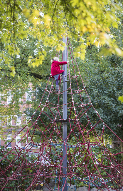 Little girl climbing on jungle gym in autumn