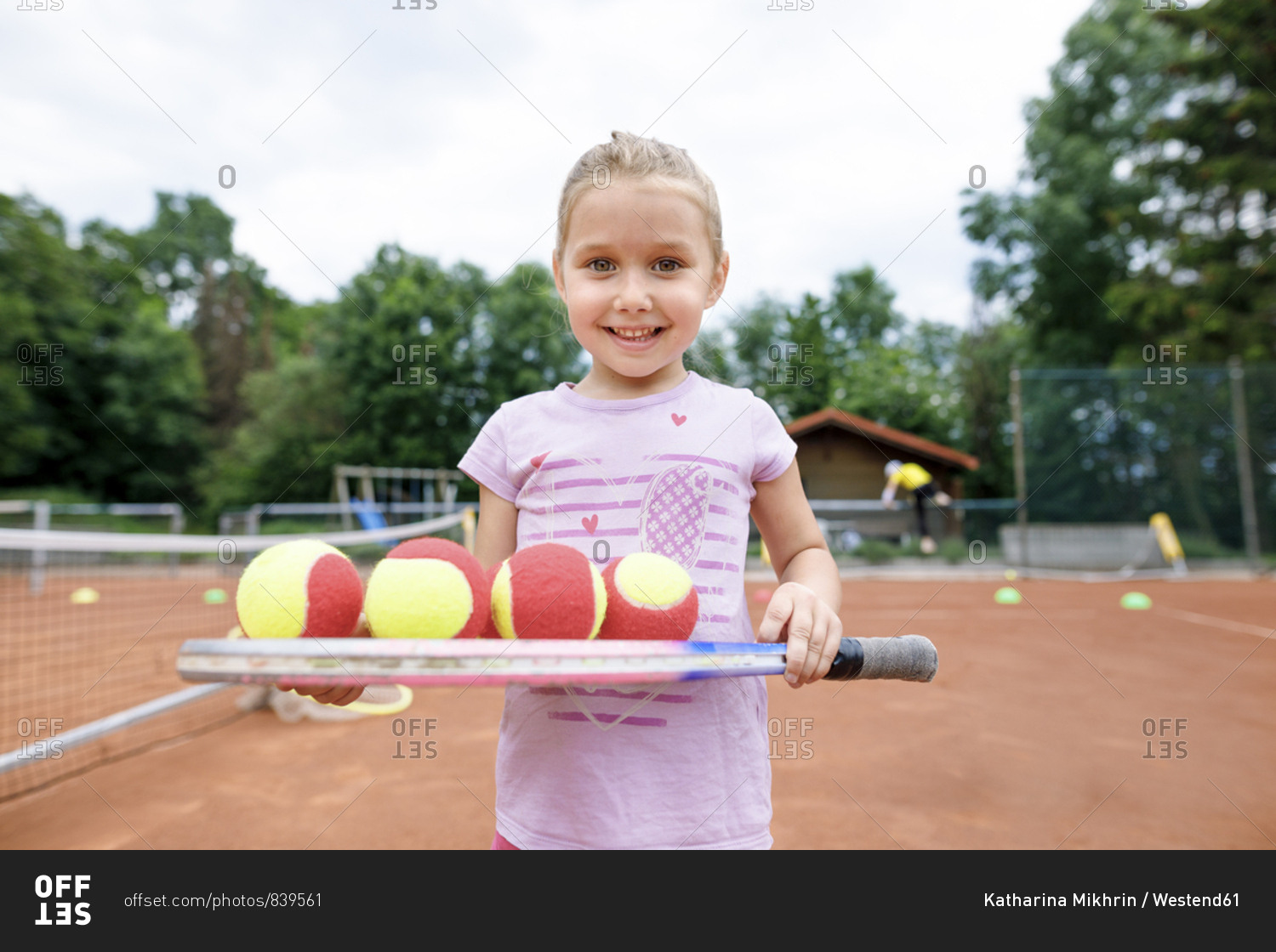 Little girl- lerning to play tennis- balancing balls on a racket