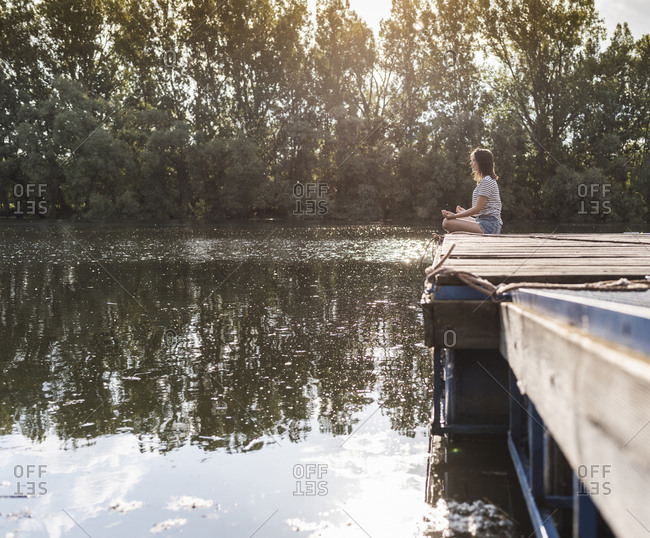 Relaxed woman sitting on jetty at a remote lake