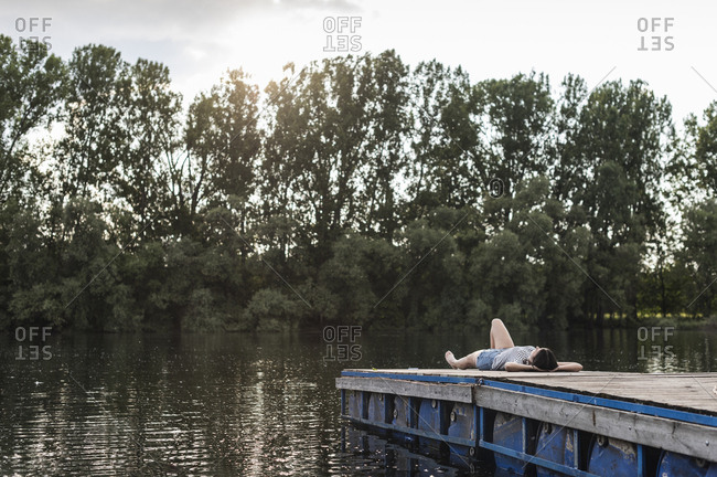 Relaxed woman lying on jetty at a remote lake