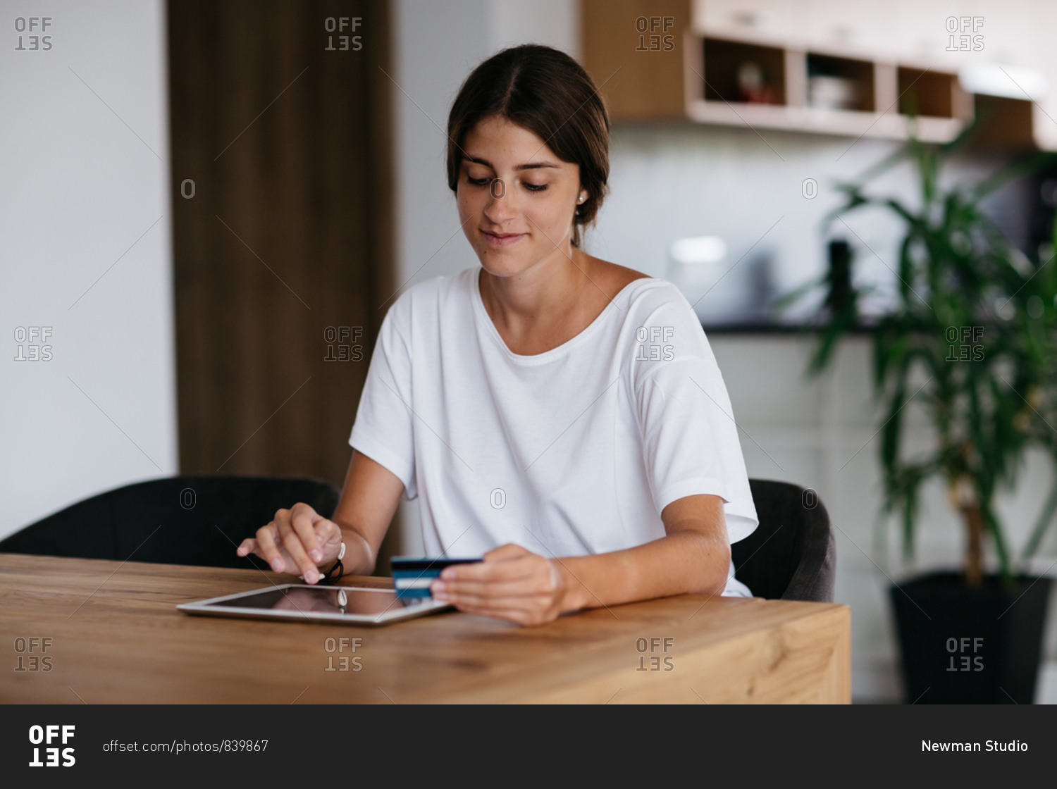 Online payment - young woman paying online with credit card at home. Cheerful woman paying bills online using digital tablet.