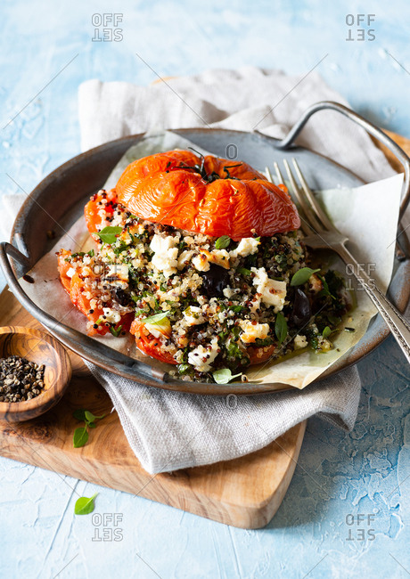 Quinoa with kalamata olives and feta cheese stuffed tomato served on rustic plate