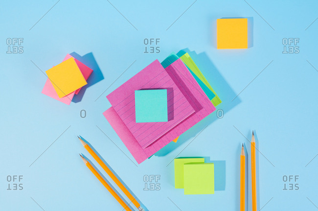 Pencils and various color sticky notes on blue background