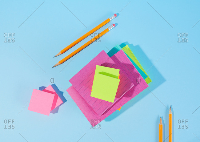 Pencils and various color sticky notes on blue background