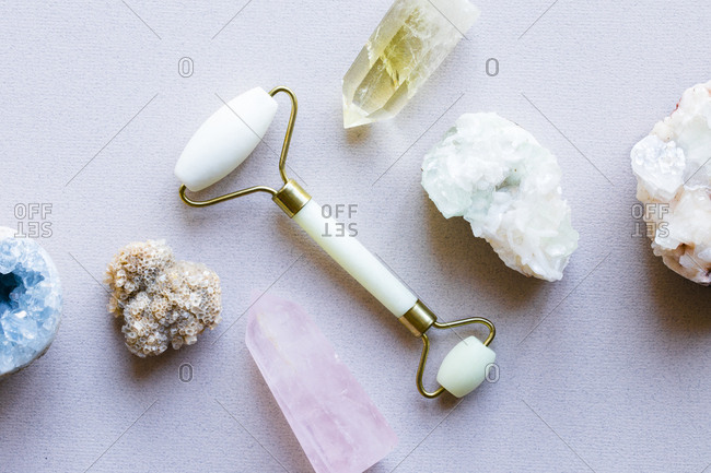 Close-up of jade facial roller surrounded by crystals and gemstones