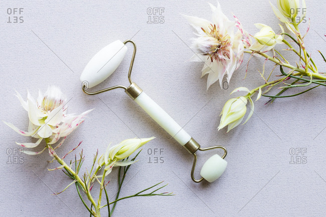 Overhead view of jade facial roller and unique flowers