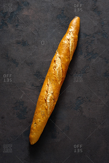 Overhead view whole baguette loaf on dark background