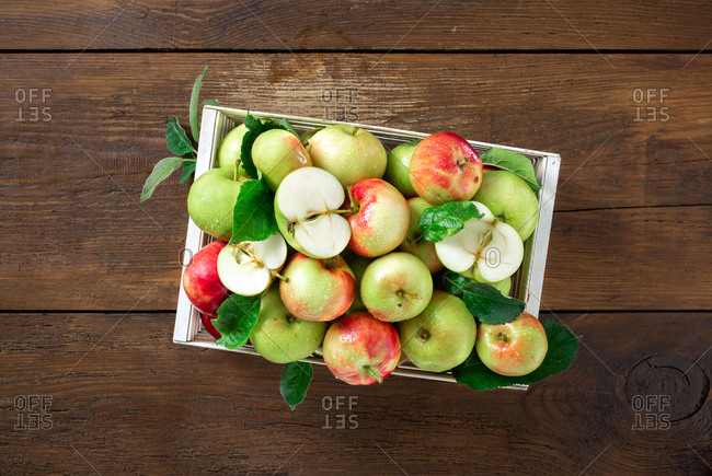 Red and green apples in wooden box on wooden table top view