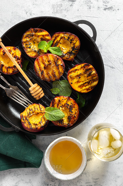 Grilled peach dessert on grill pan with cold tea and honey top view