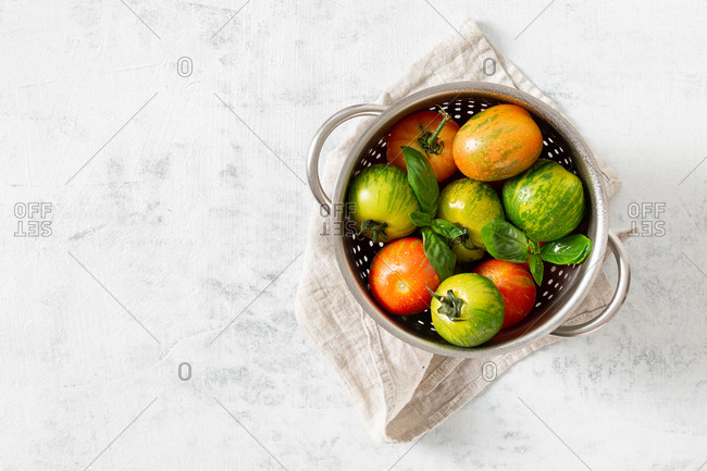 Various washed tomatoes in a sieve overhead view