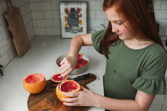 Girl preparing a grapefruit snack in the kitchen