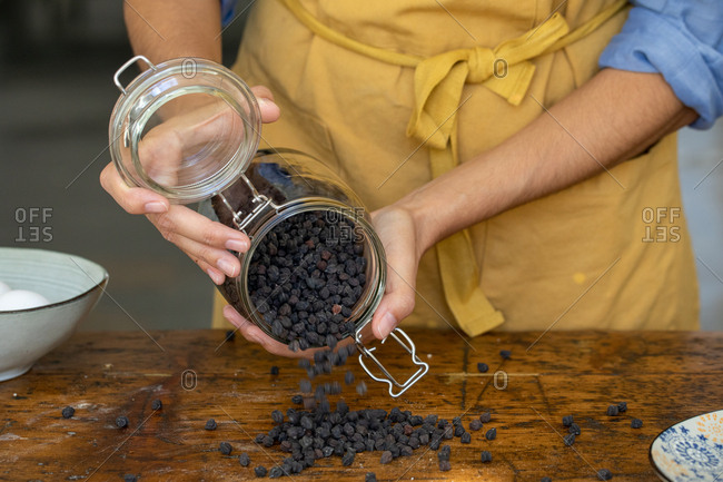 Black peppercorn being dumped onto wooden surface
