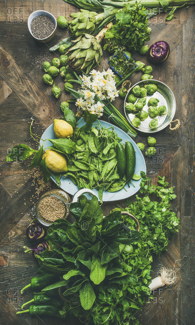 Green vegetables, fruit, seeds, sprouts, flowers, greens over wooden background