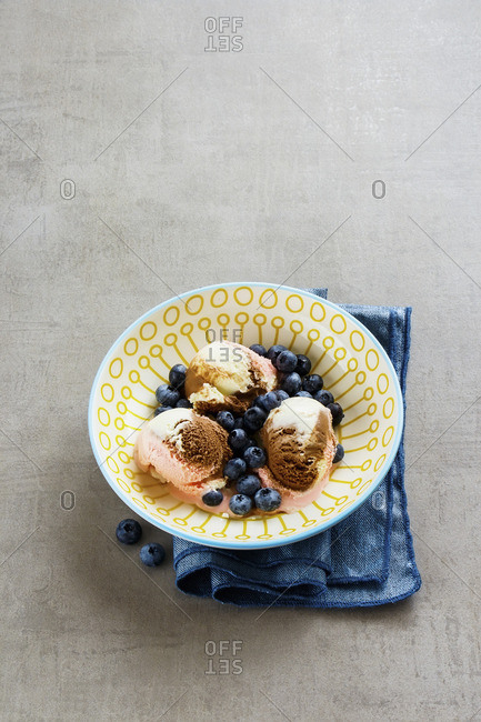 Bowl of pink, chocolate and vanilla ice cream scoops with fresh blueberry