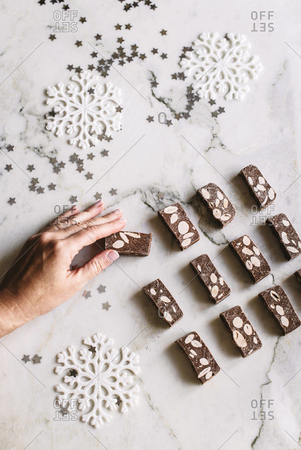 Person putting tasty chocolate nougat sweets on table