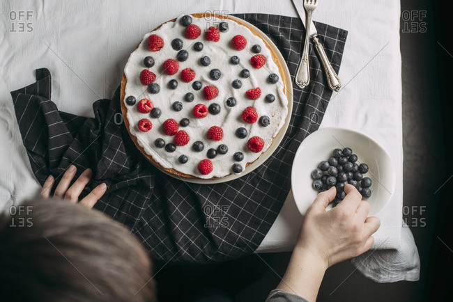 Preparing berries cake with yogurt frosting