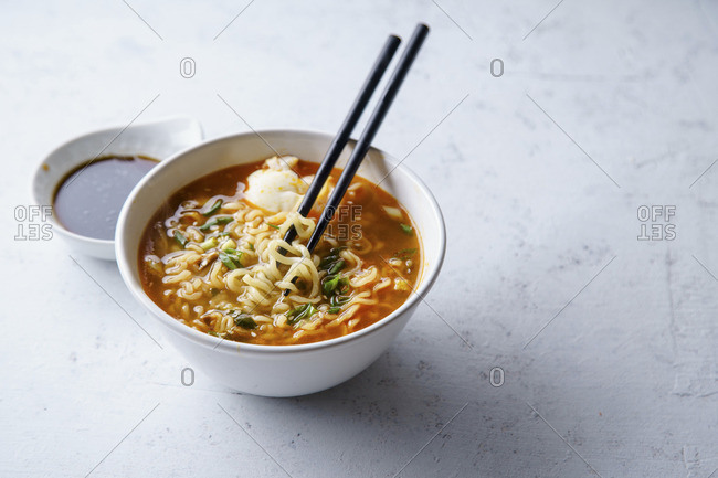 Easy japanese ramen with noodles, pork broth, egg and leek in white bowl on concrete background with copy space
