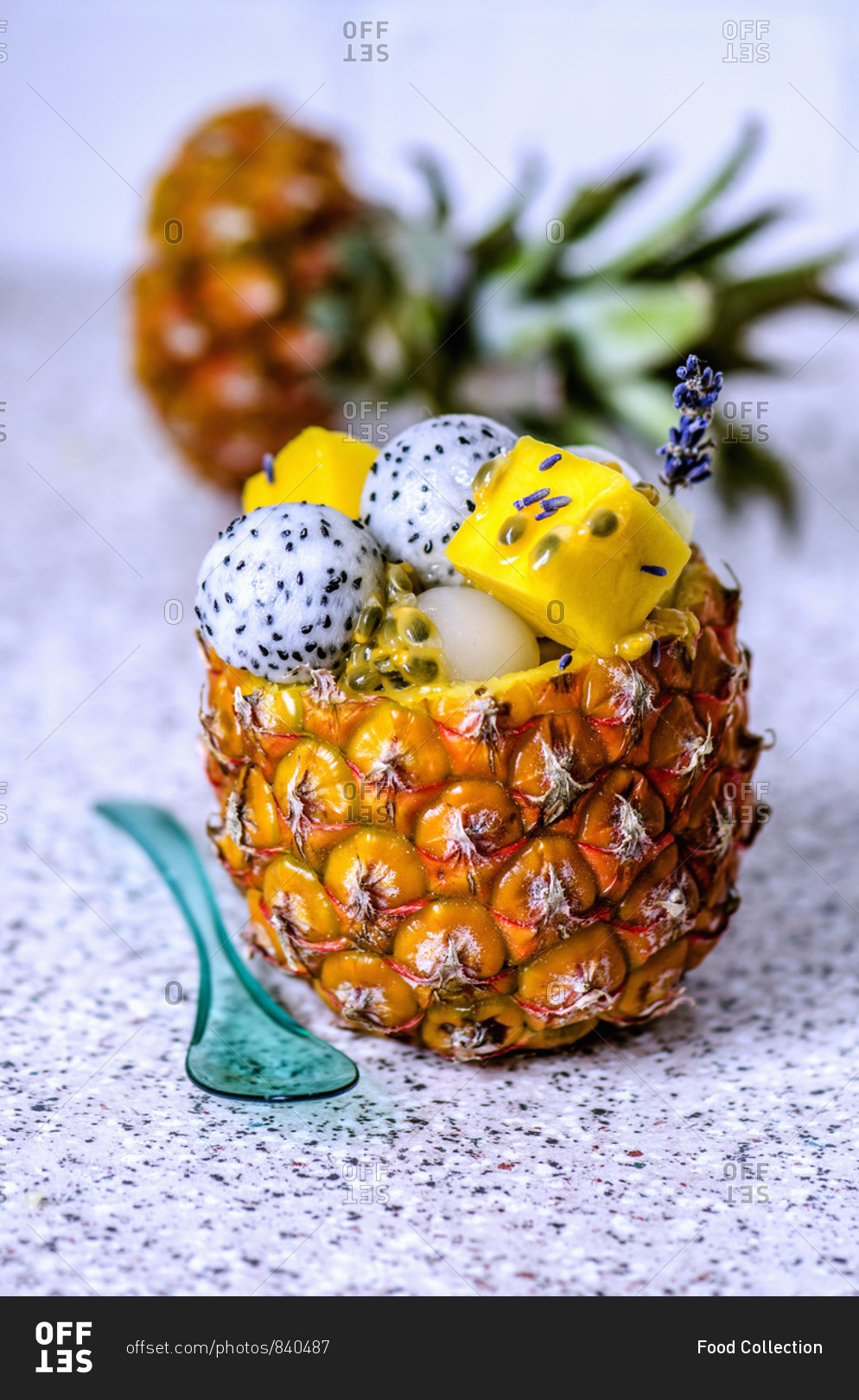 Fruit salad with various tropical fruits in a pineapple with blue transparent spoon