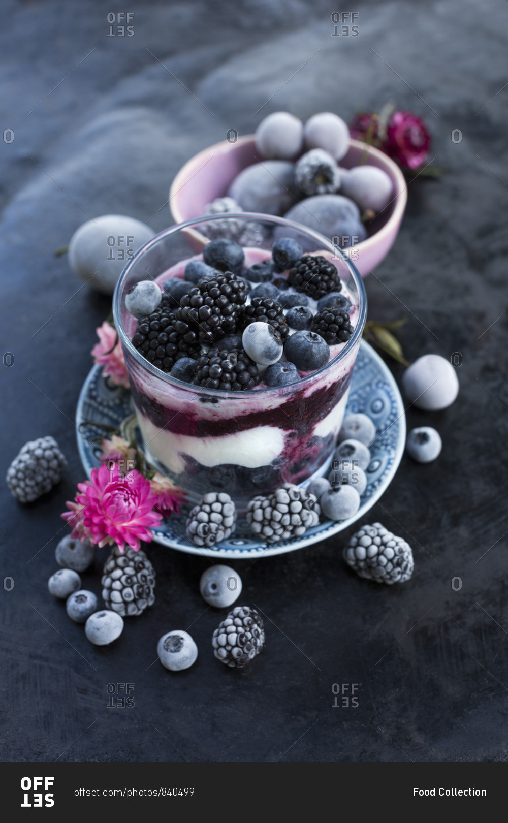 A layered dessert with fresh yoghurt, berry mash, frozen blueberries and blackberries