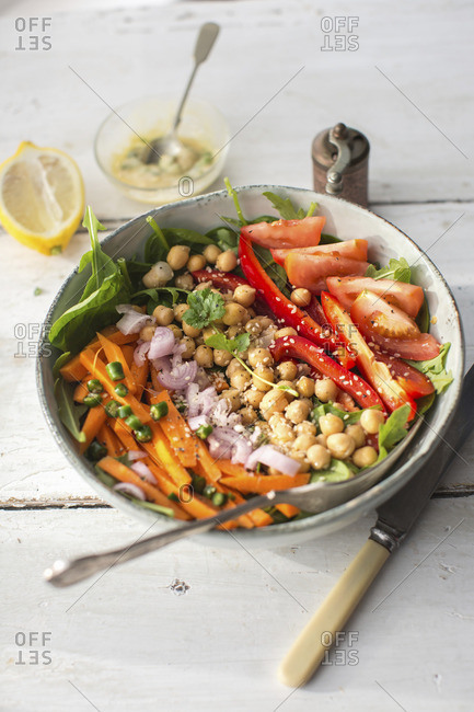 A salad bowl with carrots, onions, chickpeas, peppers and tomatoes