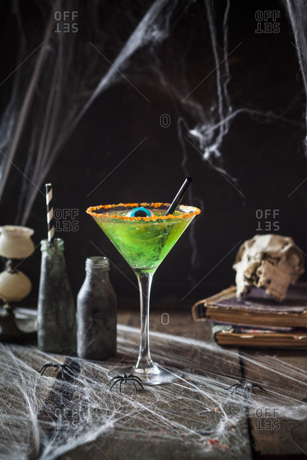 A children's cocktail made from green jelly and apple juice decorated with an eye sweet for Halloween